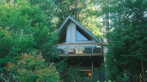 Una baita con un balcone, immersa in una fitta foresta.