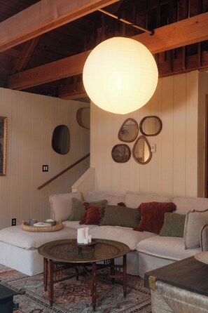 Ein gemütliches Wohnzimmer mit einem weißen Sofa, einem runden Couchtisch und einer Pendelleuchte.