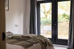 A bedroom with a bed, a window, and a view of the outdoors.
