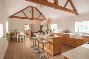 A spacious kitchen with wooden beams, a central island with bar stools, and a view to the dining area.