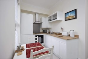 A compact kitchen with white cabinetry, a microwave, toaster, and a kettle on the countertop. - Immaculate Apartment | Historic Lincoln | Wi-Fi (Lincoln)