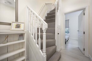 A staircase with white balusters, a framed picture, and a sign on the wall. - Immaculate Apartment | Historic Lincoln | Wi-Fi (Lincoln)