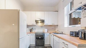 A compact kitchen with white cabinets, a built-in oven, a dishwasher, and a window above the sink. - Perfect for Contractors | Central Location | Wi-Fi (Nottingham)