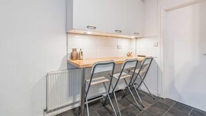 A compact kitchen with white cabinets, a wooden countertop, and a radiator. - Perfect for Contractors | Central Location | Wi-Fi (Nottingham)