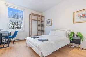 Une chambre à coucher comprenant un lit, une table de chevet, une chaise, une fenêtre et une étagère en bois.