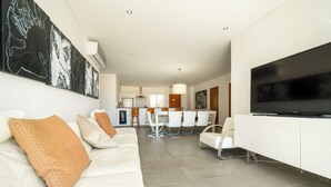Ein modernes Wohnzimmer mit einem weißen Sofa, einem Flachbildfernseher und abstrakter Kunst an der Wand.