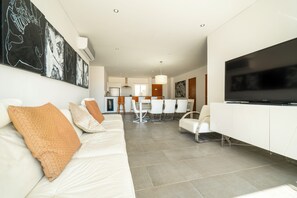 Ein modernes Wohnzimmer mit einem weißen Sofa, einem Flachbildfernseher und abstrakter Kunst an der Wand.