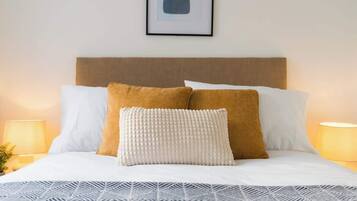 A neatly made bed with a patterned bedspread, two pillows, and a framed number on the wall.