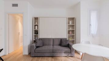 Una sala de estar moderna con un sofá gris, una mesa de centro blanca y estanterías empotradas.