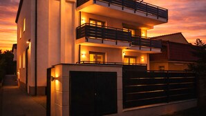 Un edificio moderno de dos pisos con balcones e iluminación exterior.