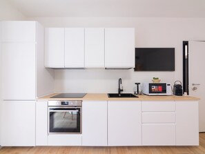 A compact kitchen with white cabinetry, a built-in oven, a microwave, and a black faucet. - GINO SUITES - Monolocali Luxury - Appartamenti vicini a Rho Fiera e Milano (Bollate)