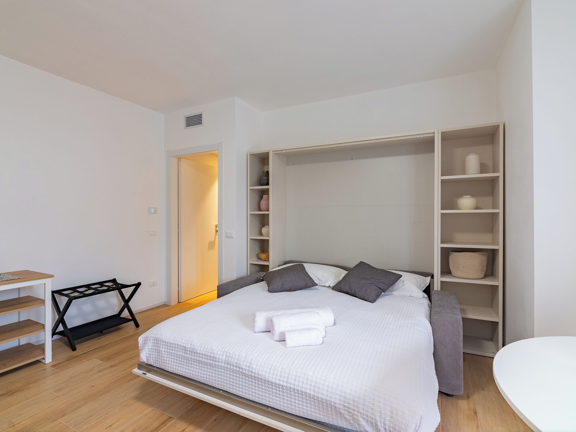 Un dormitorio con cama, mesita de noche, silla, armario y escritorio.