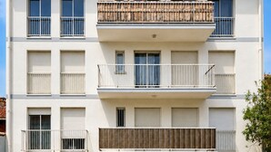 Een meerlaags woongebouw met balkons, een garage en een parkeerplaats.