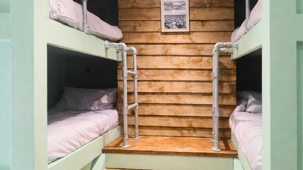 Habitación con literas, paredes de madera y un cuadro enmarcado.
