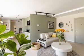 Ein modernes Wohnzimmer mit einer Couch, einem Couchtisch und einer großen Pflanze.