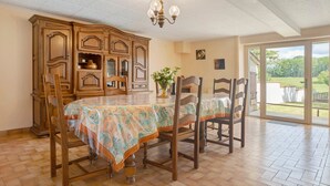 Un coin repas comprenant une table, des chaises, un buffet en bois et une vue à travers une porte vitrée.