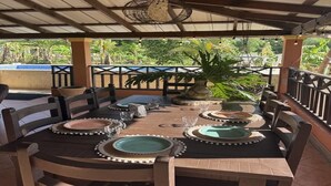 A covered outdoor dining area with a wooden table set for four, surrounded by chairs. - A hidden ecological gem, a private Villa, in Salcedo, Dominican Republic (Salcedo)
