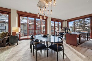 A modern kitchen with a central island, large windows, and a dining area with a round table and chairs. - Solaris 2A South - 3 Bedroom (Vail)