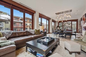 A spacious living area with a leather sofa, a coffee table, and a dining area with a chandelier. - Solaris 2A South - 3 Bedroom (Vail)