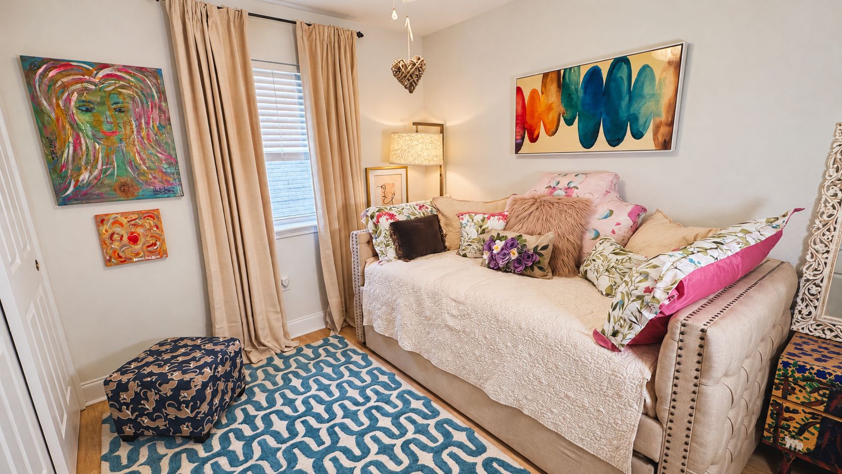 A bedroom with a bed, a nightstand, a lamp, and artwork on the walls.