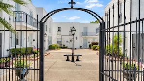 A gated entrance to a building with a central lamp post and a bench.