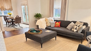 A modern living room with a grey sofa, a coffee table with decorative items, and a dining area with a table and chairs.