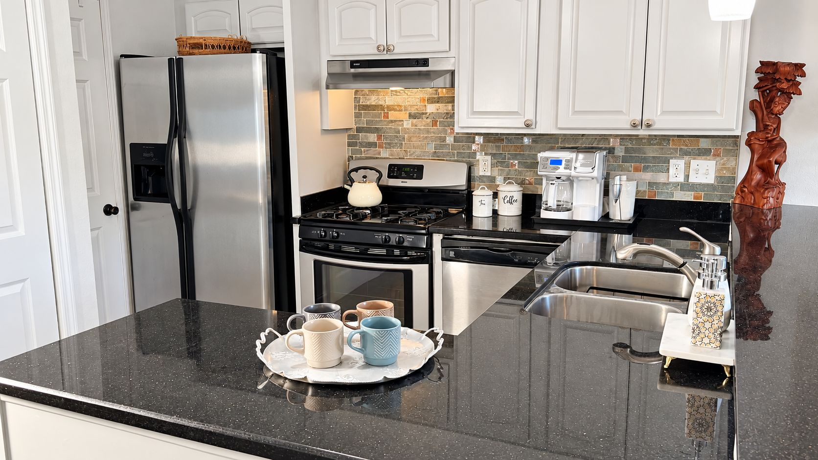 A kitchen with a stainless steel refrigerator, a gas stove, a dishwasher, and a coffee maker.