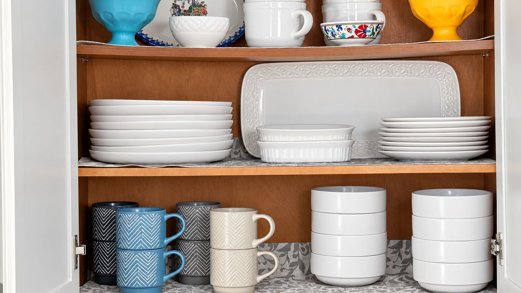 Un meuble contenant des assiettes et des tasses blanches, dont certaines sont ornées de motifs décoratifs.