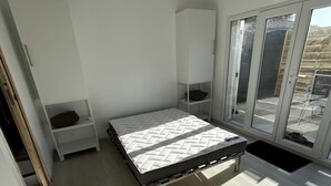 Une chambre à coucher avec un lit, une armoire, une petite table et une fenêtre donnant sur un beau paysage.
