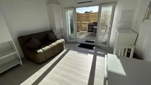 Un salon moderne avec un canapé, une table basse et une porte-fenêtre coulissante donnant sur un espace extérieur.