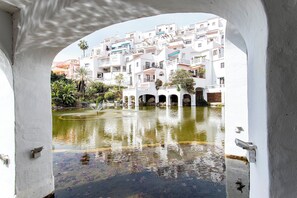 A view through an archway of a white building with a courtyard and a fountain. - Casa Bengeo - Two Bedroom Apartment, Sleeps 4 (Nerja)