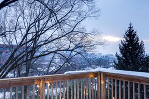 A wooden deck with snow on the railing, overlooking a cityscape with buildings and trees. - Walkable Condo Near Over-the-Rhine & Hard Rock! (Cincinnati)