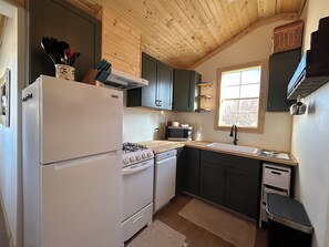 Una cocina compacta con refrigerador, estufa, microondas y pileta.