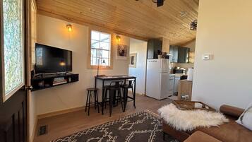 Un salon chaleureux avec un canapé marron, un tapis à motifs et un téléviseur.