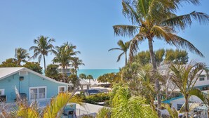 Ein Küstengebiet mit einem hellblauen Gebäude, Palmen und Blick auf den Strand.