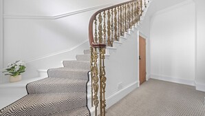 A staircase with a decorative railing, white walls, and patterned carpet. - The Manor - Beachwalk Apartments (North Lanarkshire)