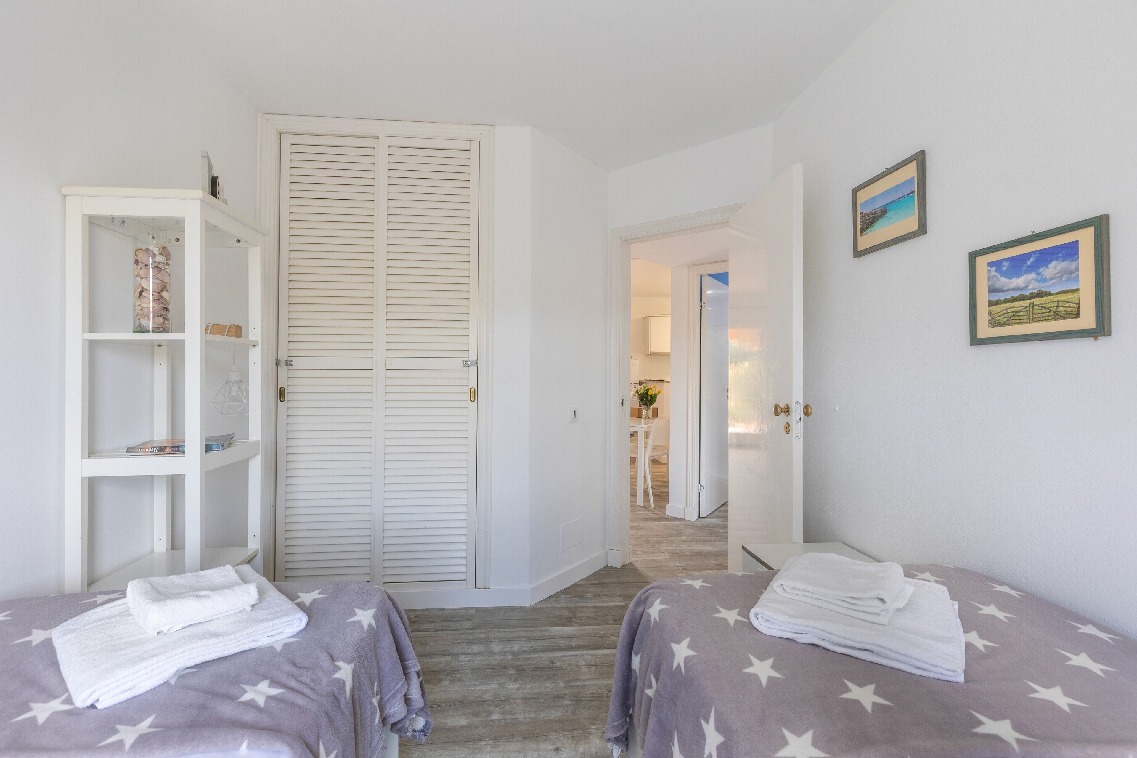 Een slaapkamer met twee bedden, een kledingkast en een deur naar een andere kamer.