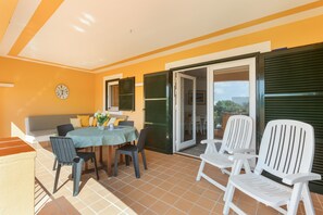 Un patio con una mesa, sillas, un sofá y un reloj en la pared.