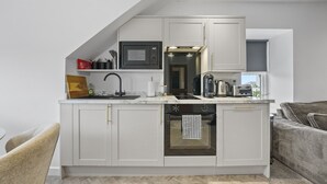 Una cocina compacta equipada con microondas, tostadora, hervidor y lavavajillas.