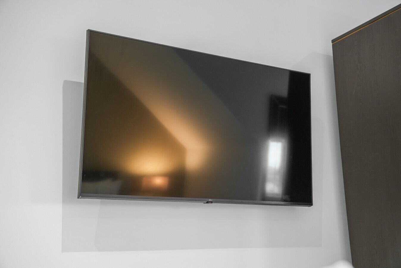 Un téléviseur à écran plat fixé à un mur blanc.