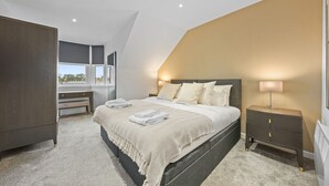 Un dormitorio con cama, mesita de noche y escritorio.
