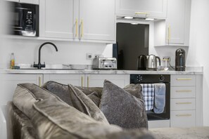 Una cocina moderna con armarios blancos, un microondas negro, una cafetera y un tostador.