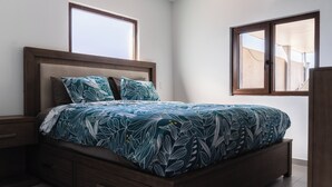 A bedroom with a bed, wooden headboard, two windows, and a nightstand. - Luxurious Villa 5 minutes from EAGLE BEACH (Noord)