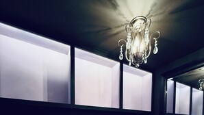 Un pasillo de diseño moderno, con una lámpara de araña e iluminación en las paredes.