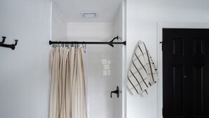 Une salle de bain avec un rideau de douche, un porte-serviettes, une porte et une serviette accrochée au mur.