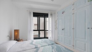 A bedroom with two beds, a wardrobe, and a window with curtains.