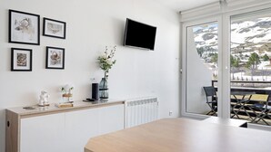 A modern room with a wooden table, a TV mounted on the wall, and framed pictures.