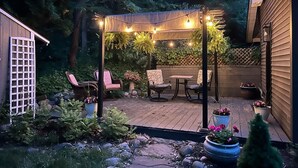 Un patio con pérgola, luces colgantes y mobiliario exterior.