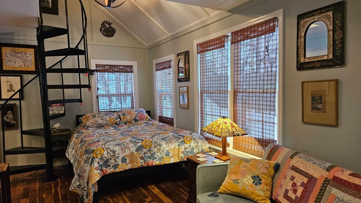 A bedroom with a bed, a chair, a lamp, and a window with a view.