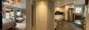 Une chambre avec un lit, un coin salon avec un canapé et une table, une cuisine équipée d’appareils modernes, et un coin repas avec une table en verre.